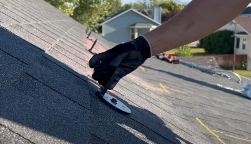 A person installing a roofing shingle