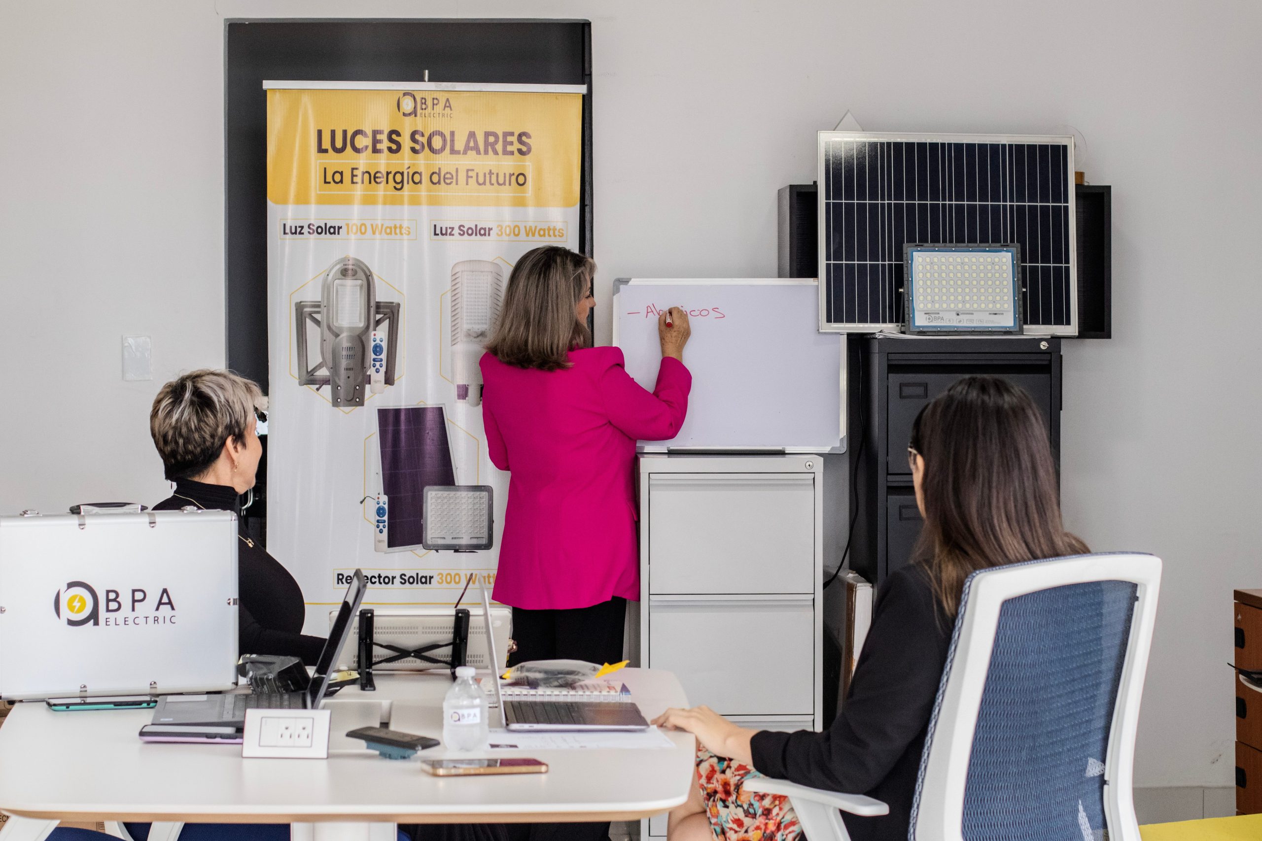 Solar energy team brainstorming around panels and a whiteboard in an office